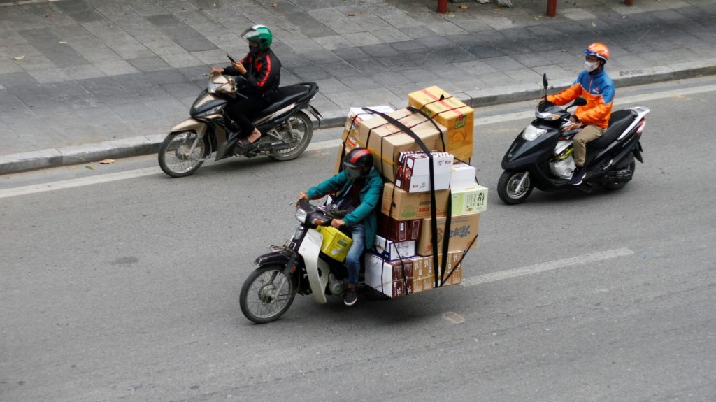 Motorcyclists carrying large loads on a street